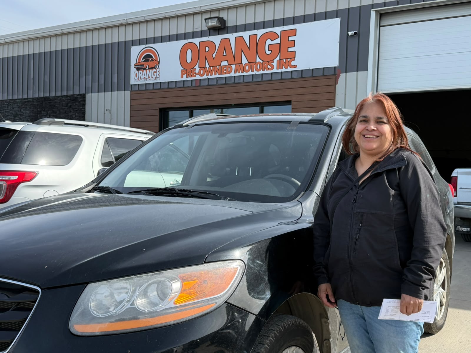 Happy Orange Auto customer with their vehicle