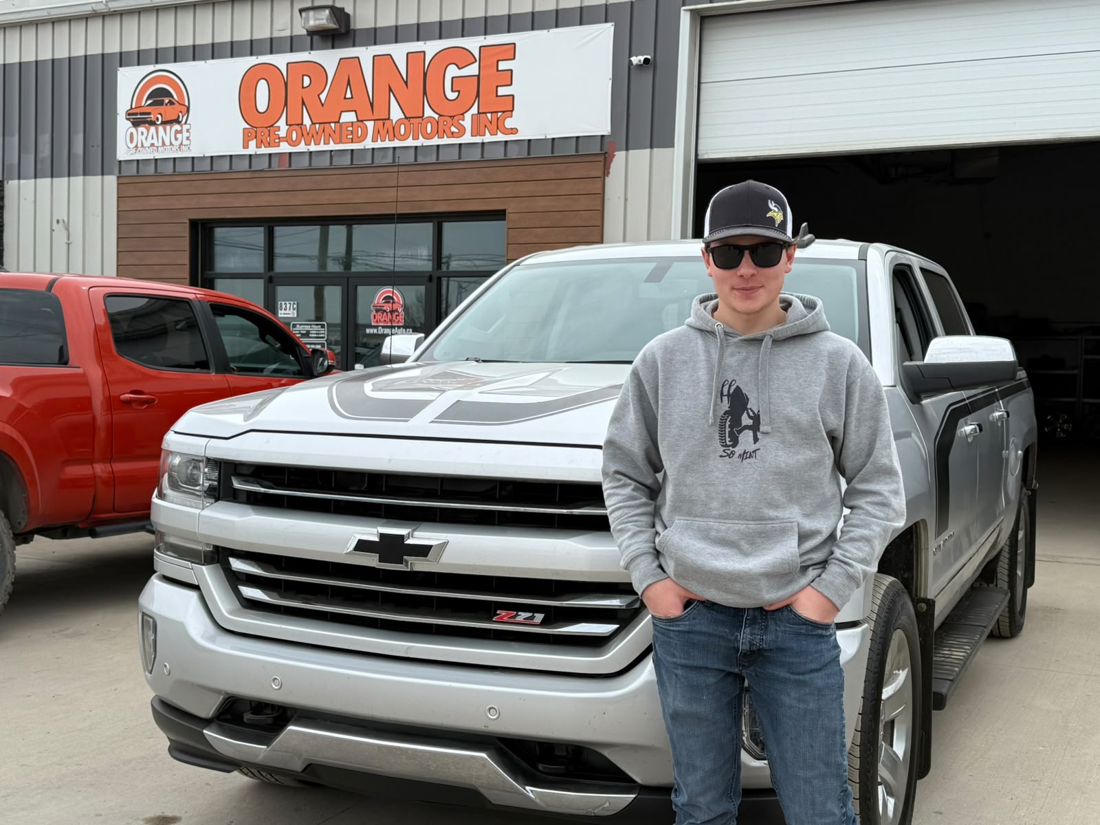 Happy Orange Auto customer with their vehicle
