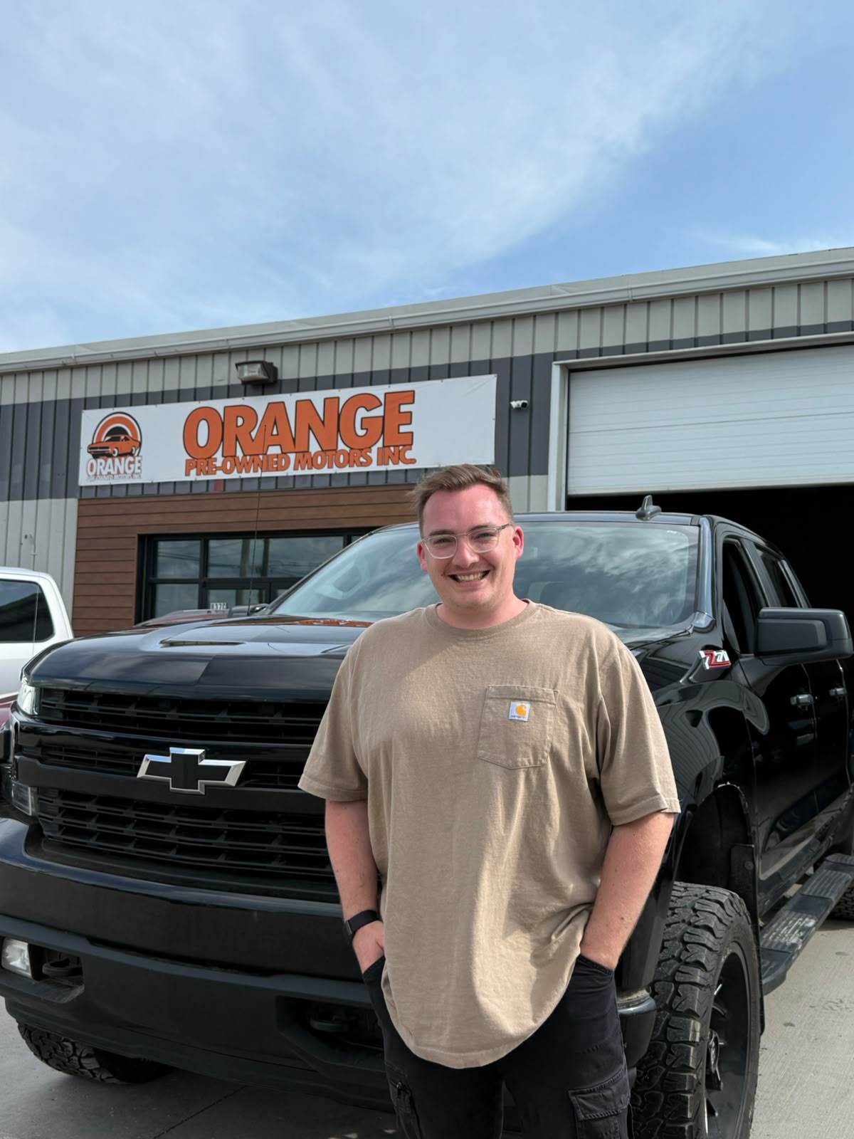 Happy Orange Auto customer with their vehicle