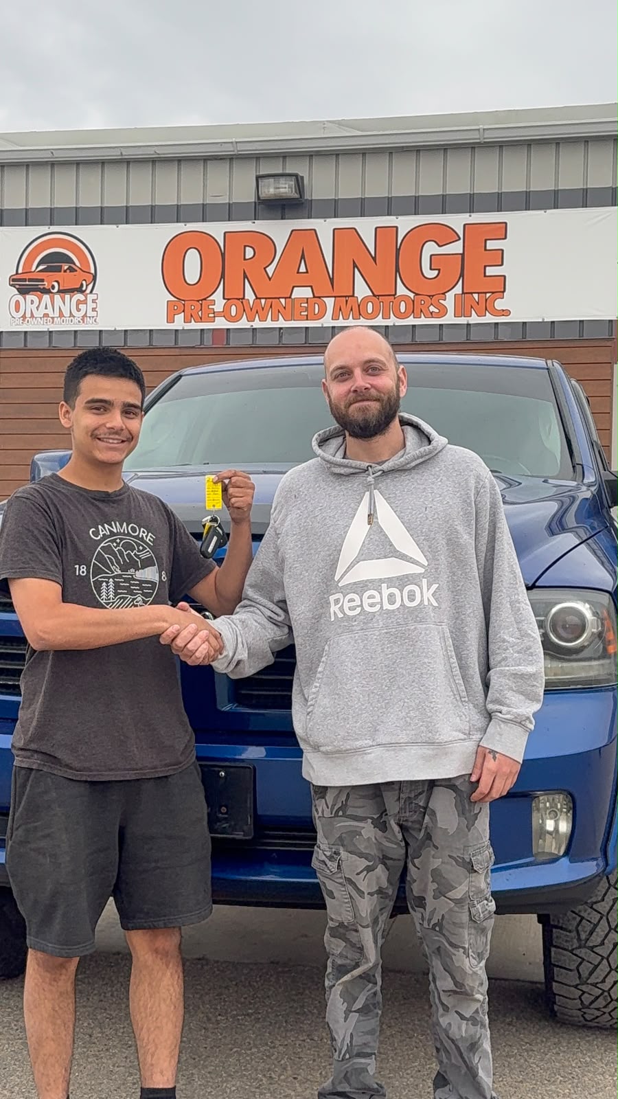 Happy Orange Auto customer with their vehicle