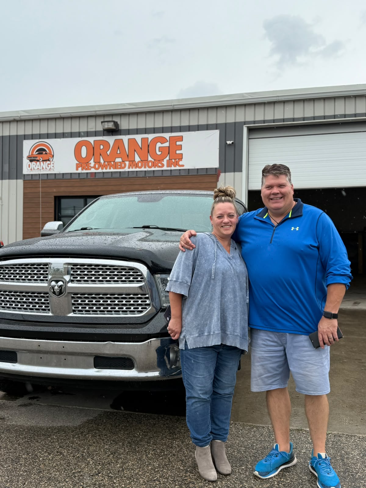 Happy Orange Auto customer with their vehicle