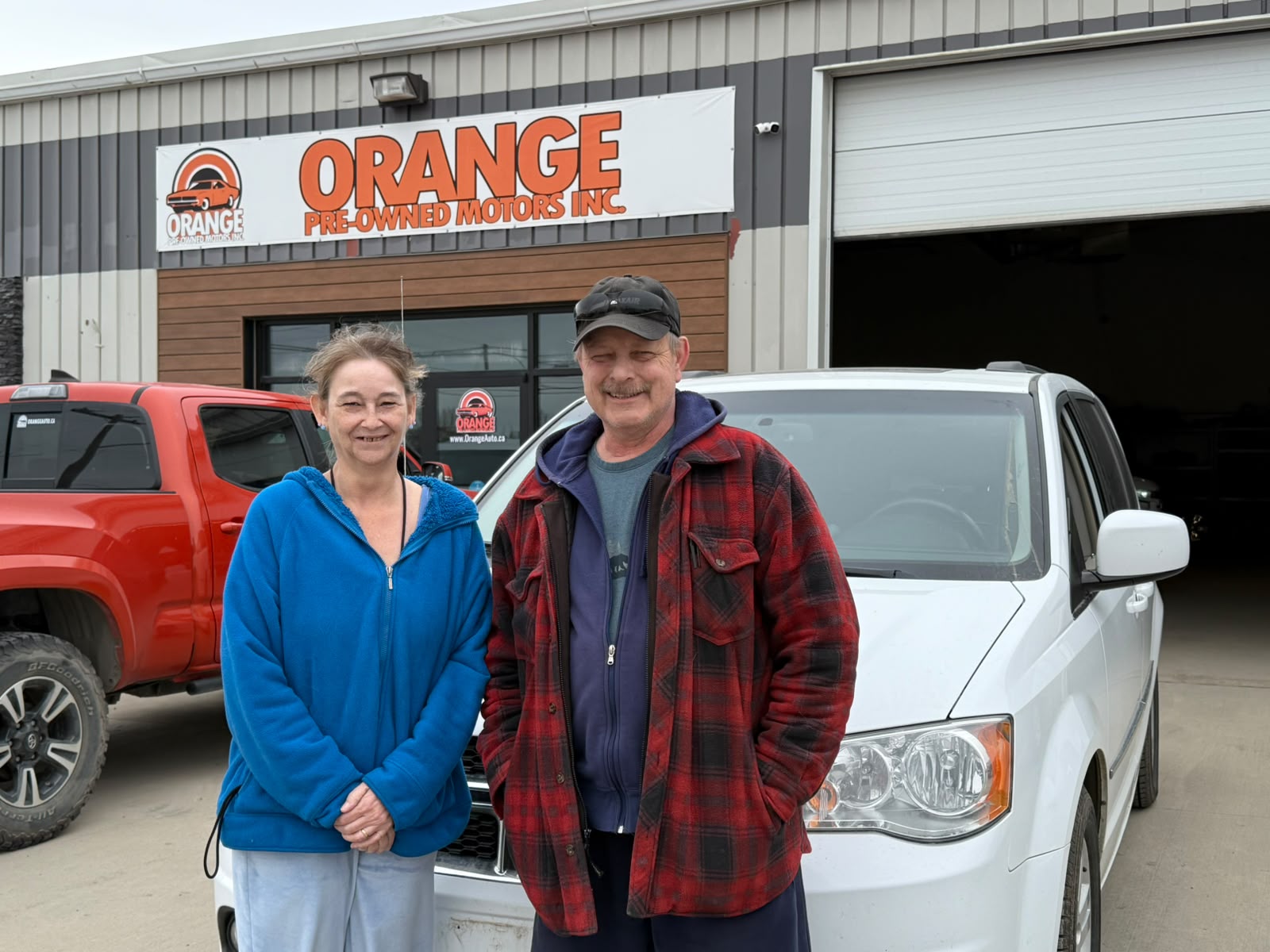 Happy Orange Auto customer with their vehicle
