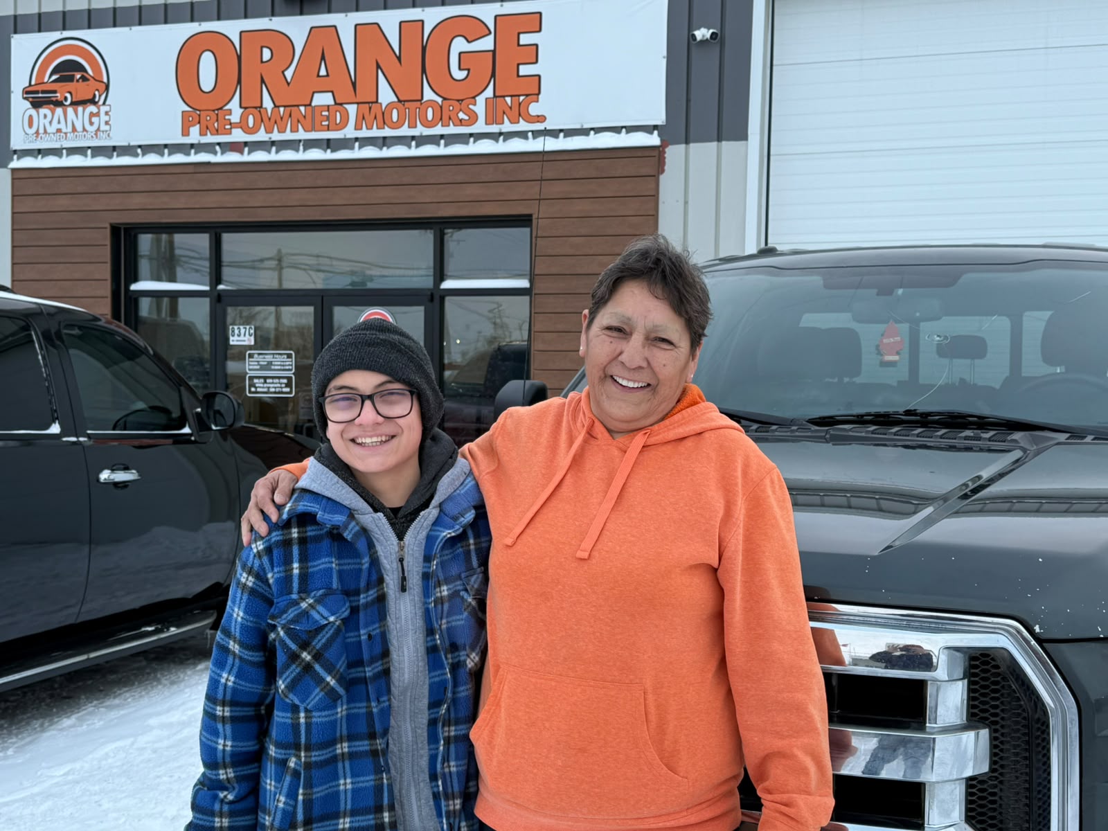 Happy Orange Auto customer with their vehicle