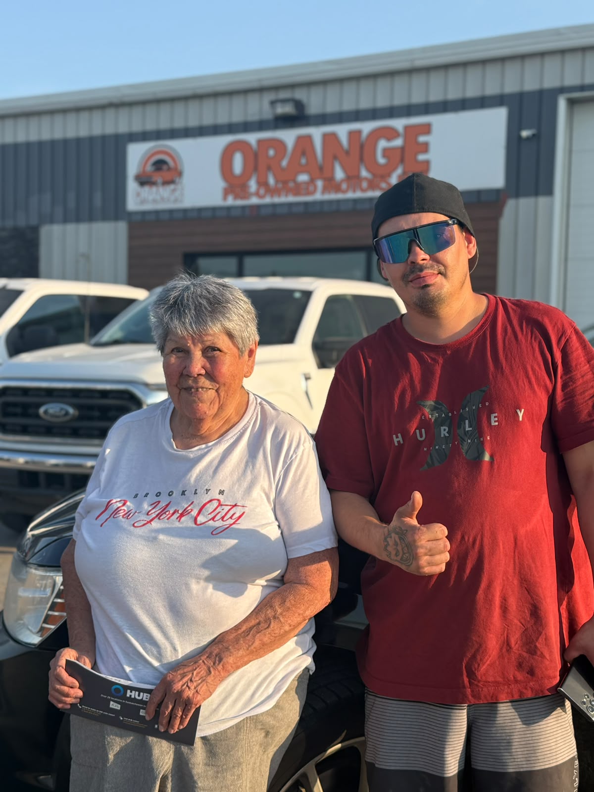 Happy Orange Auto customer with their vehicle
