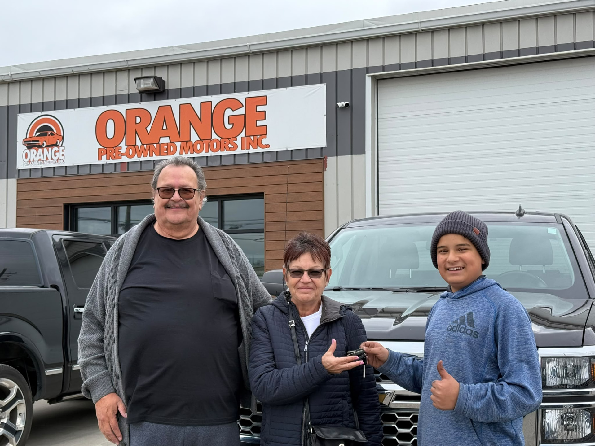 Happy Orange Auto customer with their vehicle